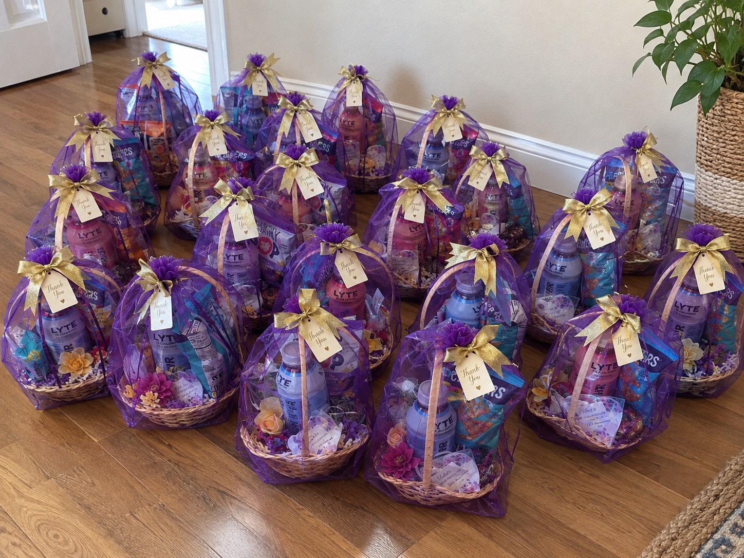 Rows of matching purple-wrapped thank-you gift baskets with gold bows